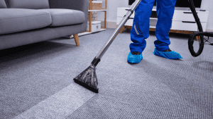 Professional carpet cleaner using a steam cleaner to deep clean a carpet in a residential home.